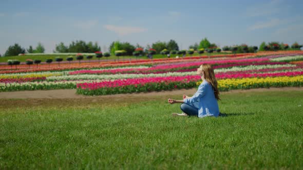 Young Woman Meditating on Green Grass alt