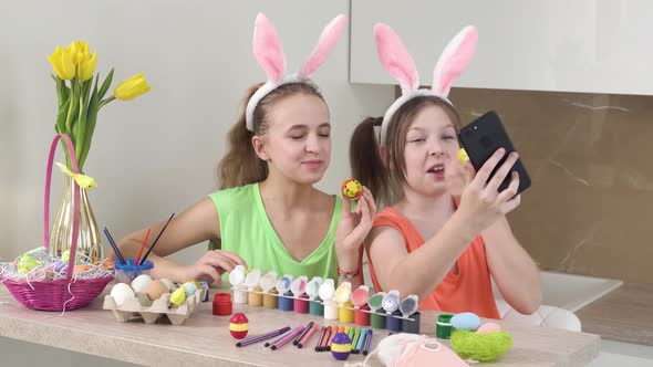 Girls with Rabbit Ears Take Selfies with a Smartphone with Easter Eggs