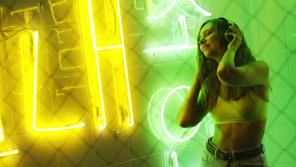 Lady in Neon Light Enjoying Music with Earphones