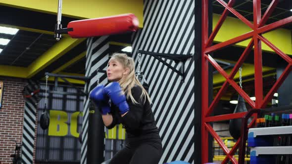 Female Athlete Practices Punches on a Simulator in the Boxing Ring