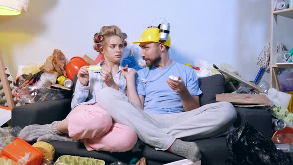 Funny looking man with bear helmet eatching tv, woman is not interesting and ignoring him. 