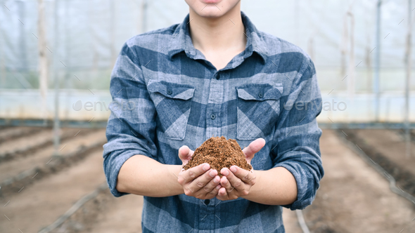 Young male agronomist holding soil and examining quality of fertile agricultural field.