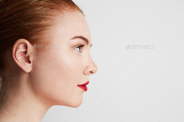 Profile portrait of beauty female redhead model with dark eyebrows and light nude make-up.