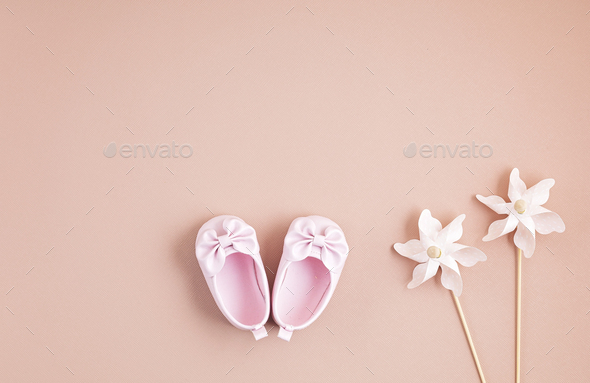 Cute newborn baby girl shoes with festive decoration over pink background.  Baby shower, birthday Stock Photo by OksaLy