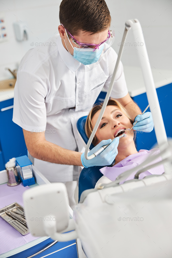 Dentist drilling woman teeth during oral dental procedure