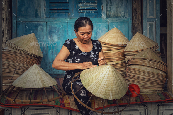Vietnamese Old woman craftsman making the traditional vietnam hat in the old traditional house