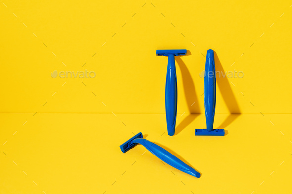 Disposable razors on yellow background, studio shot
