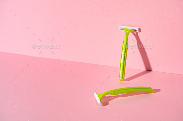 Female disposable razors on pink background, studio shot
