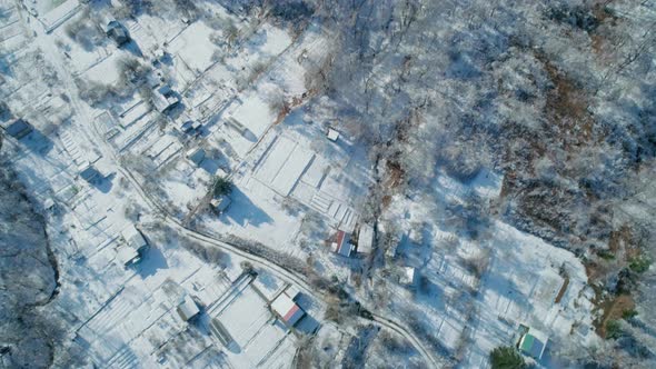 Aerial Tilt View of a Winter Village Mountains and a Frozen Forest with Snow and Ice Covered Trees alt