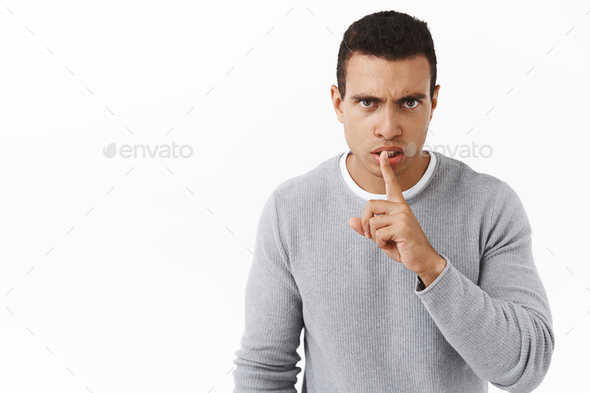 Shut up or else. Serious-looking angry young man scolding someone being too loud, shushing, make
