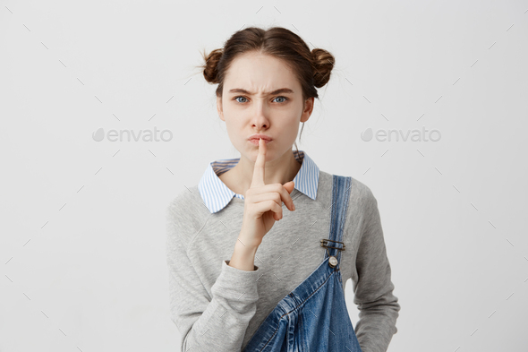Responsible female speaker seriously gazing on people demanding silence with body language. Adult