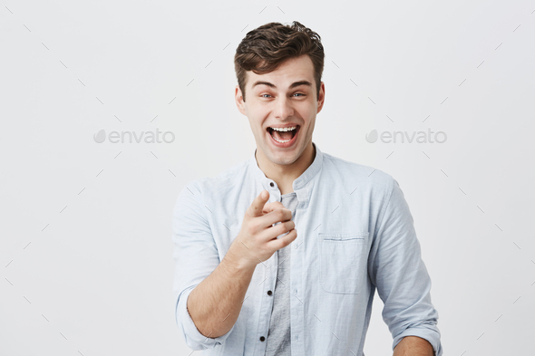 Advertising concept. Excited cheerful european man wearing light blue shirt raising eyebrows and