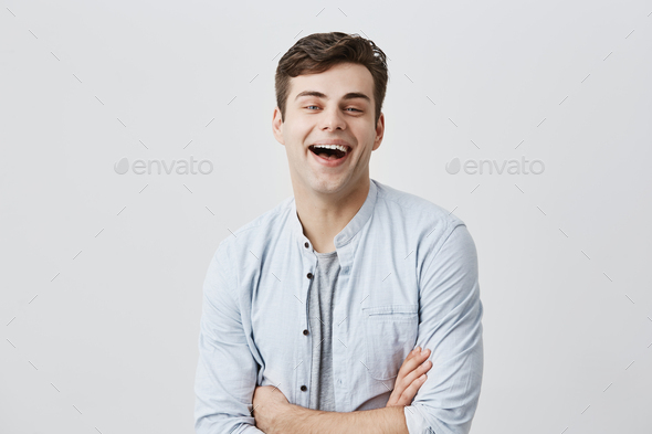 Cheerful young european smiling broadly with teeth, rejoicing at positive news or promotion at work