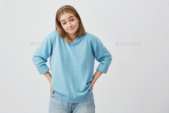 Clueless Puzzled Caucasian Girl Dressed In Sweater And Jeans Shrugging Shoulders Keeping Her