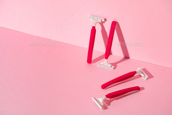 Pink disposable razors on pink background, copy space