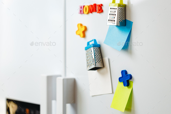 Sheets of paper and magnets on fridge door in kitchen