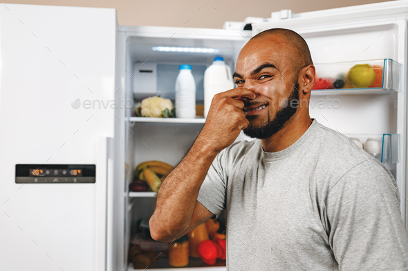 African american man closing nose because of bad smell from fridge