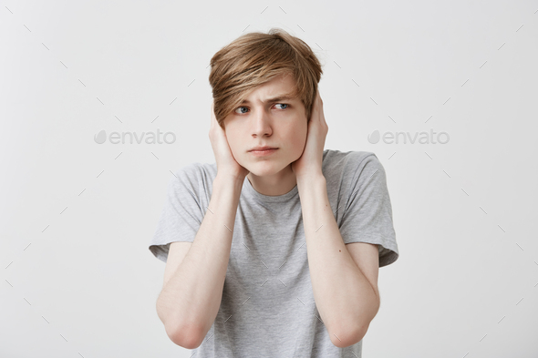 I don`t want to hear it! Fair-haired young male with serious and irrirared face expression, annoyed
