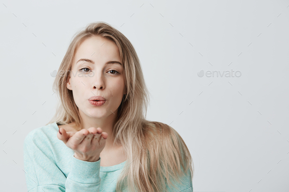 Attractive caucasian woman posing with kiss on her lips with blonde dyed hair, having flirty look