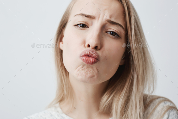 Close-up portrait of young attractive caucasian woman posing with kiss on her lips with blonde dyed