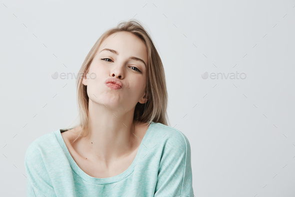 Young attractive caucasian woman dressed in blue casual clothes posing with kiss on lips with blonde