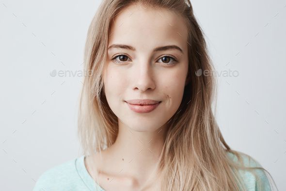 Beautiful female having dark shining eyes, pure skin and blonde straight hair wearing loose sweater