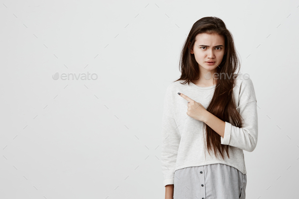 Check this out Studio shot of beautiful brunette girl in casual clothes pointing with index finger