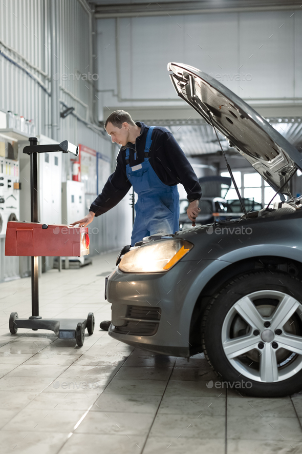 Worker checks and adjusts the headlights of a car's lighting system