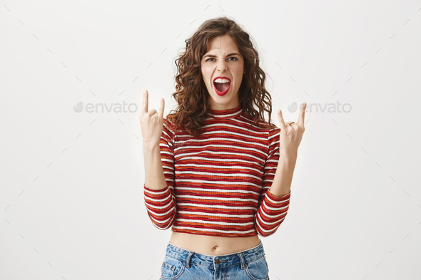 Rock n roll is alive. Emotive playful good-looking female showing rock gesture with both hands and