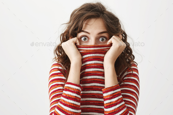 Maybe no one will notice me like this. Portrait of funny cute curly-haired female hiding in sweater