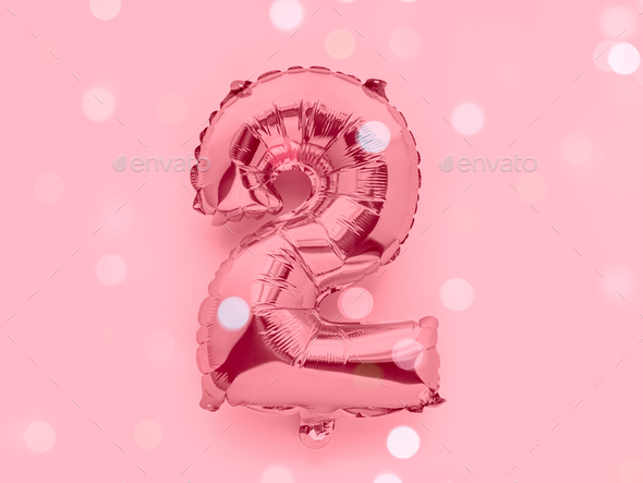 Number 2 rose gold foil balloon party decor on pink background, birthday concept with lights
