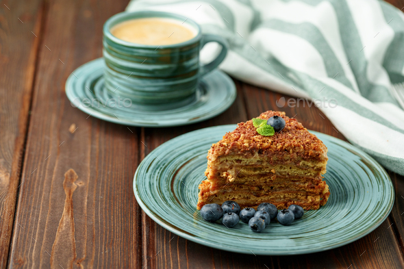 Piece of honey cake with nuts on green plate