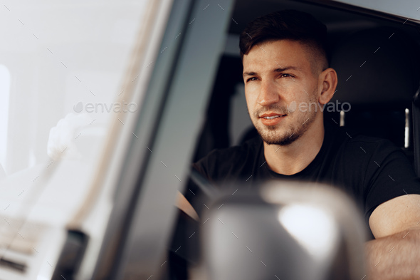 Handsome young man driver looking through the window of his off-road car - Stock Photo - Images