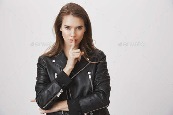 Shh, listen to me. Attractive beautiful european woman holding index finger over mouth, looking