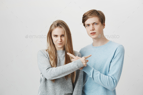 Siblings trying to accuse each other in front of angry mom. Serious unhappy couple with fair hair