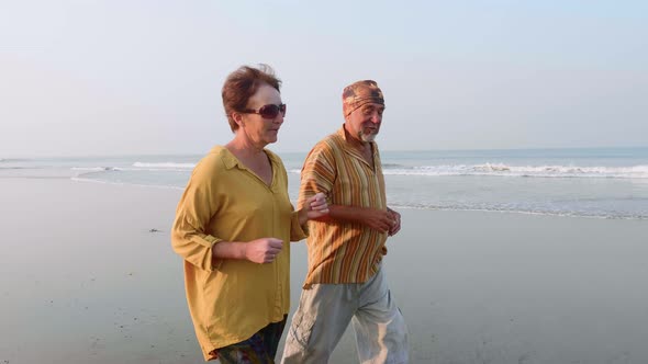Active Senior Couple Running on the Sandy Beach at Sunrise