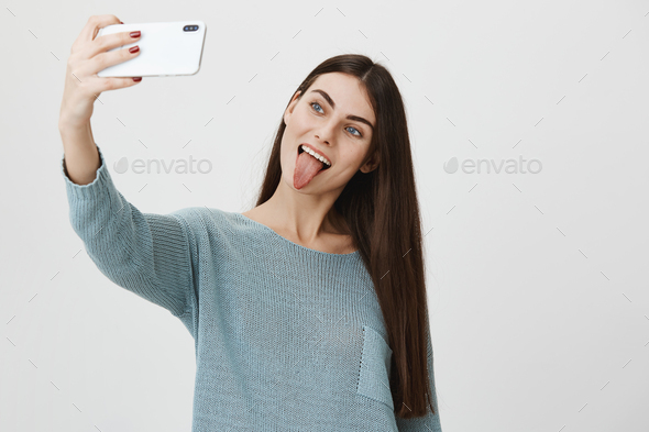 Attractive And Trendy Brunette Raising Hand While Taking Selfie On Smartphone Sticking Out 
