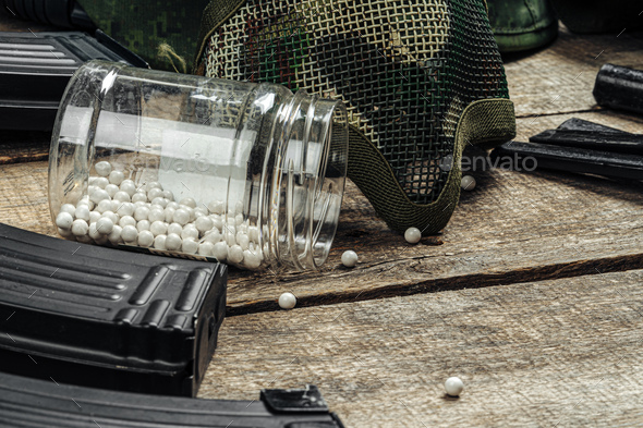 Close up of airsoft gun magazine and airsoft balls on wooden background - Stock Photo - Images