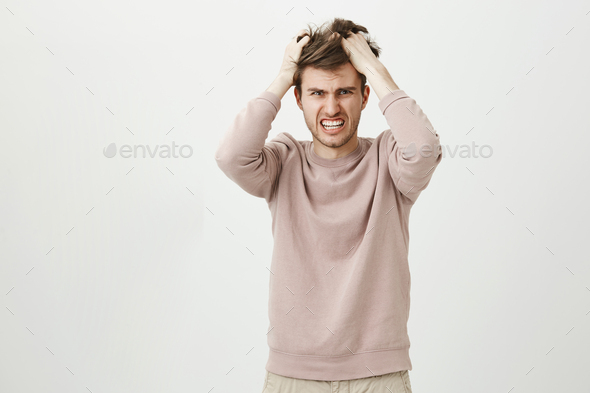 Portrait of very angry caucasian man pulling out his hair, being mad looking with furious expression