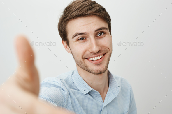 Here, let me lend you hand. Portrait of charming friendly caucasian man pulling hand towards camera