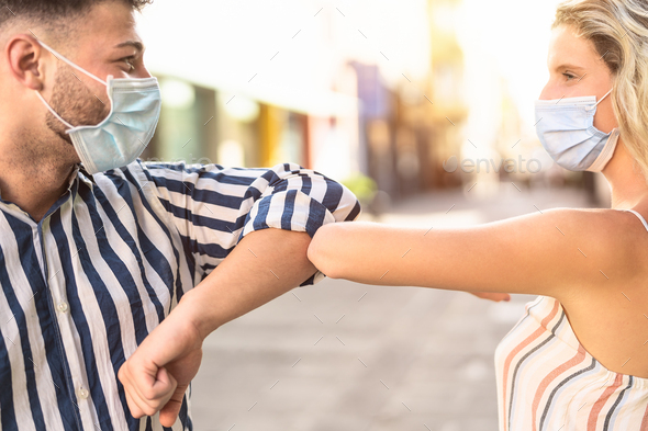 Young friends wearing face surgical mask doing new social distancing greet with elbow