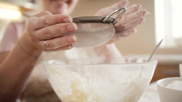 Slow Motion of Young Woman Making Dough and Sifting Flour with Metal Sieve alt