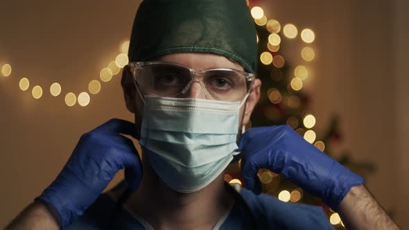Doctor takes off his mask and smiles at Christmas alt