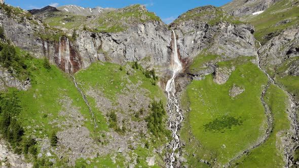 Aerial: drone flying over scenic waterfall and mountain stream on the italian Alps alt