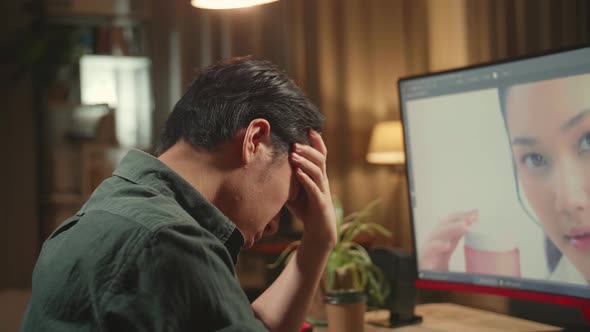 Tired Asian Male Digital Editor Works In Photo Editing Software On His Personal Computer alt