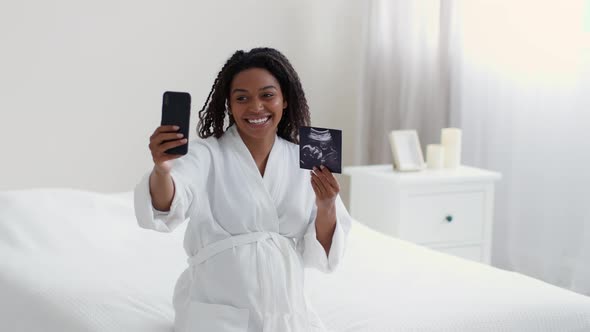 Young Happy Pregnant Lady Video Chatting with Friends Via Cellphone Showing Sonogram and Talking to alt