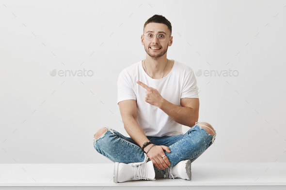It was not me, it was him. Indoor shot of embarrassed cute boyfriend in stylish outfit sitting on