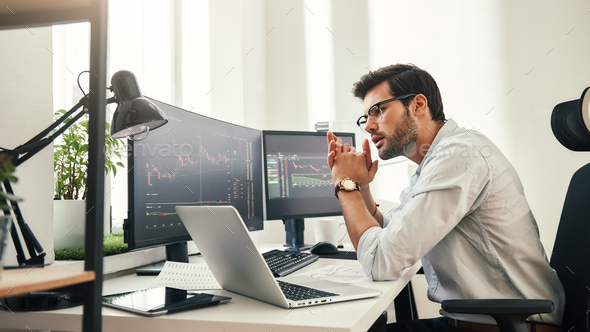 Trading strategy. Successful young trader in eyeglasses looking at analyzing trading charts on - Stock Photo - Images