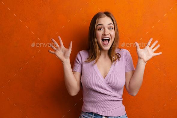 Young ginger excited woman showing her palms and screaming at camera