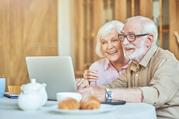 Smiling elderly couple watching funny video on computer Stock Photo by  friends_stock